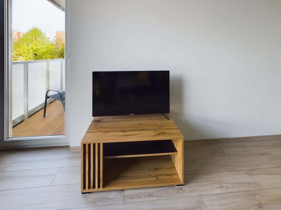 Living room with an access to the furnished balcony and a cabinet for handy trinkets with television, which has an acceess to cable channels.