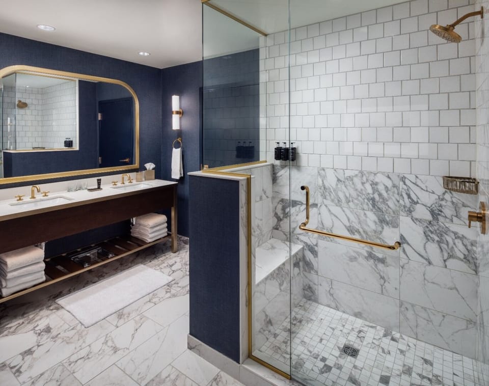 Step into a polished bathroom with marble finishes and glass shower.