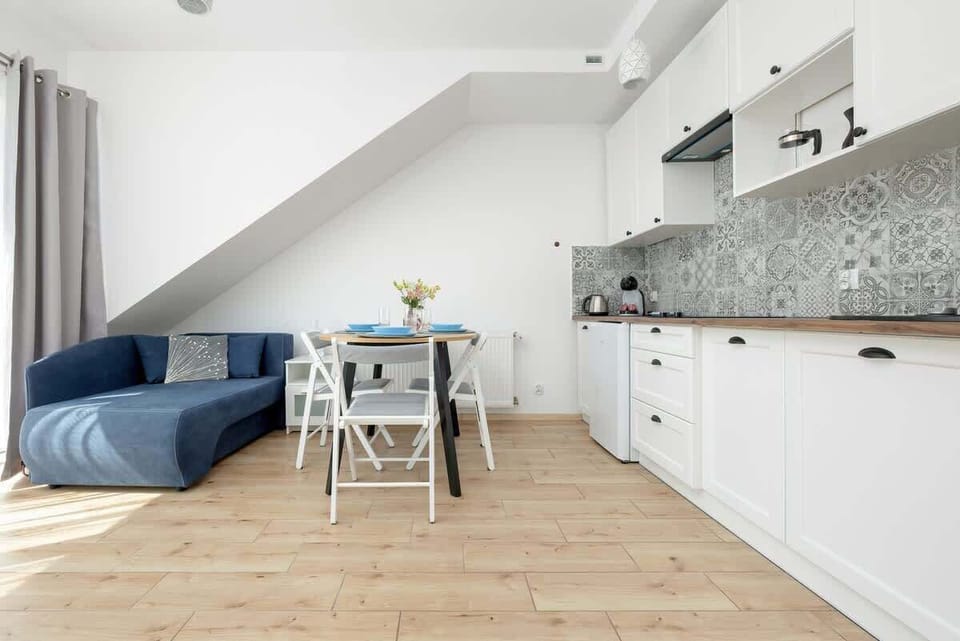 The open kitchenette to the living room, equipped with white furniture, ensures convenience and cohesive design.