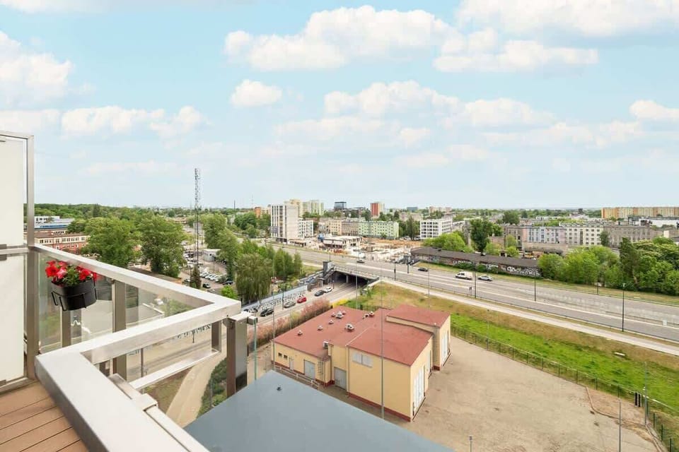 The view of the city from behind the balcony railing on a sunny day reveals the modern urban landscape.