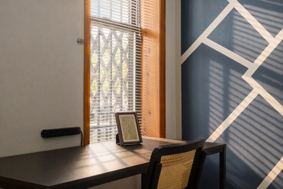 Serene primary bedroom featuring a plush queen bed, designer accent wall, and a dedicated workspace for maximum productivity