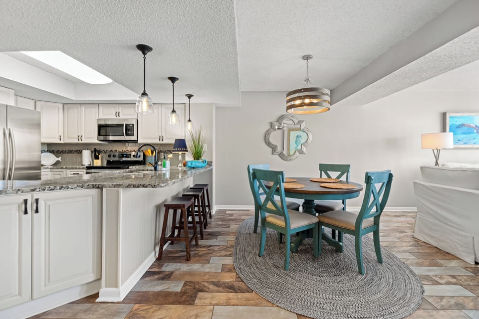 Open dining area with table sitting for 4 and 3 on bar stool at counter top.