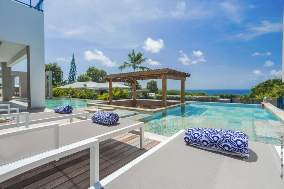 Designer sun loungers and infinity pool with panoramic sea views in Saint-François.