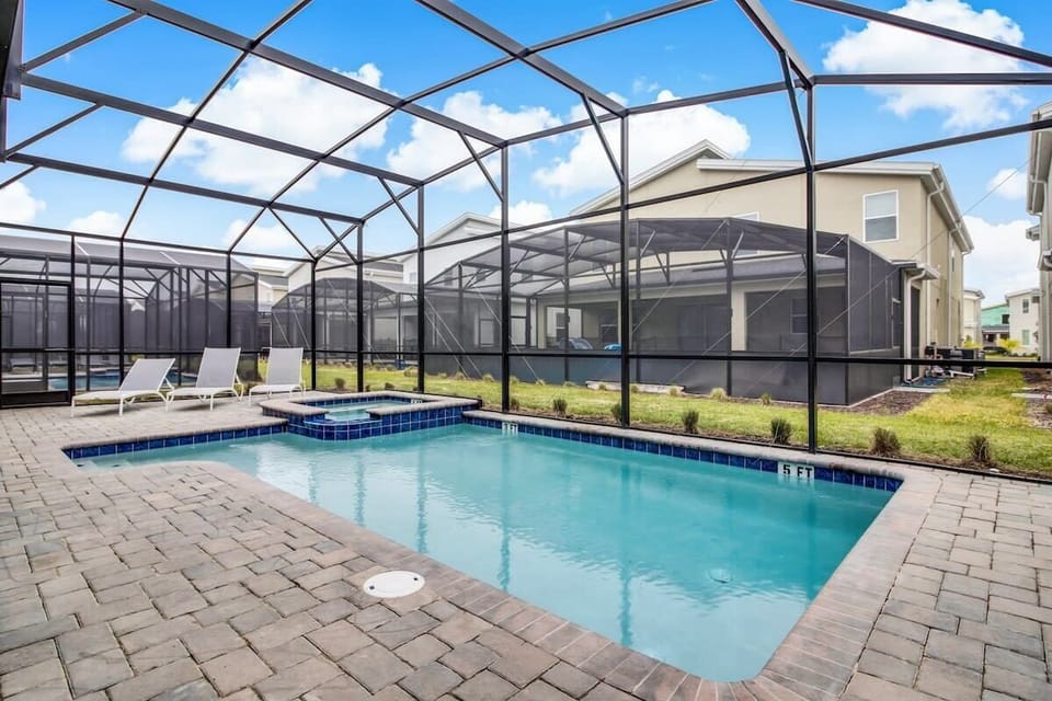 Relax in your private screened pool oasis with a hot tub and lounge chairs, perfect for unwinding under the sun.