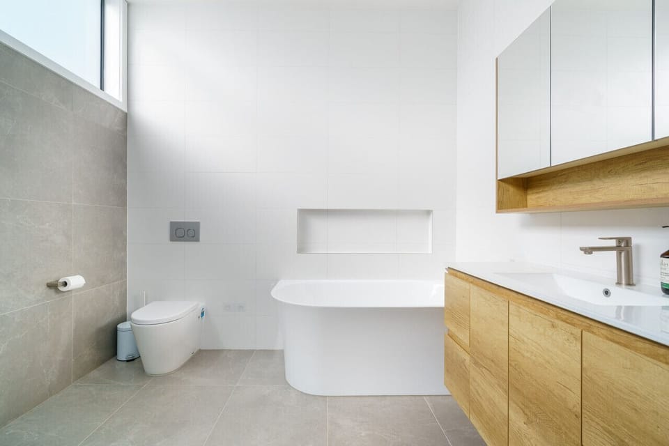 Indulge in luxury within this sleek and spacious bathroom, complete with a walk-in shower, modern fixtures, and a luxurious oversized bathtub. Appreciate the clean lines and abundant natural light in this impeccably designed space.