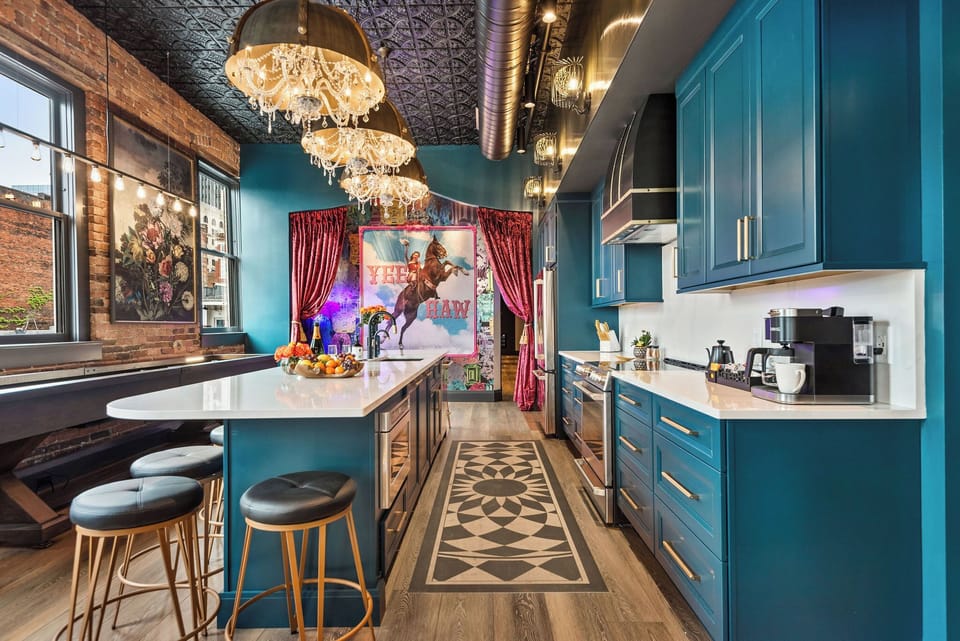 - Spacious kitchen with bold teal cabinets and bright lighting   - Long island, modern appliances and welcoming seating blend   - Perfect cooking space with stylish design and photo-ready charm