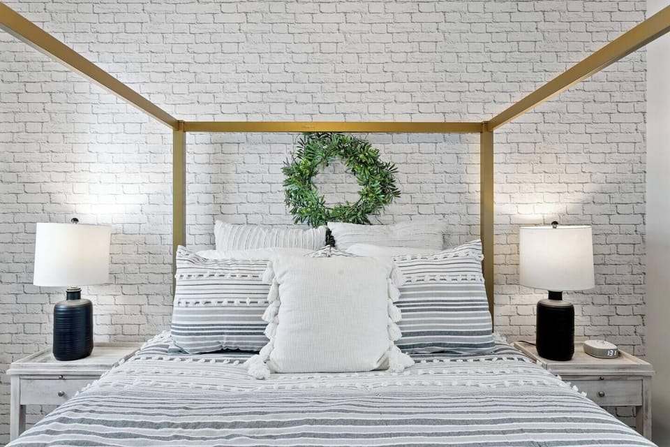 This tranquil bedroom offers the perfect environment for relaxation and rejuvenation.  Unwind in comfort on the plush queen-size bed bathed in natural light from the beautiful window.  Ample lighting fixtures and bedside tables with lamps on each side ensure you have the perfect ambiance for reading or winding down before bed.  This light-filled haven is your personal oasis within the home