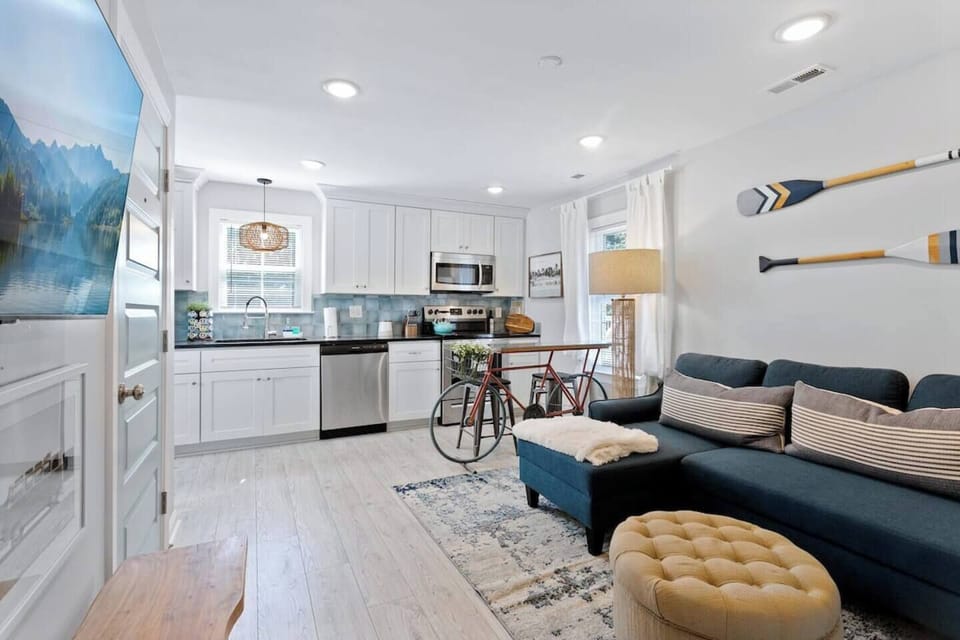 This inviting living room features a comfy sofa, perfect for movie nights or unwinding after a long day.  The sleek entertainment center with a smart TV provides the perfect spot to stream your favorite shows or movies.  Unique wall art like a paddle design and a bike motif throughout the space adds a touch of personality.  This stylish and comfortable haven is perfect for rela...