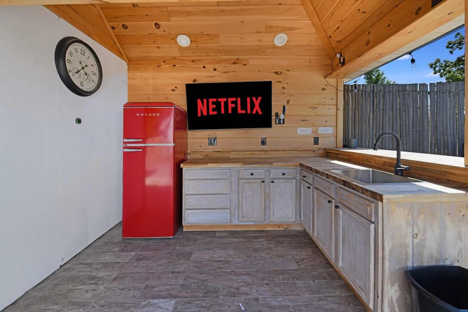 rustic kitchenette with a red retro refrigerator and a mounted television