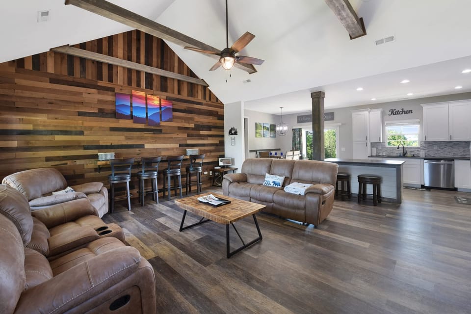 Spacious living area with vaulted ceilings and rustic wood accent wall.