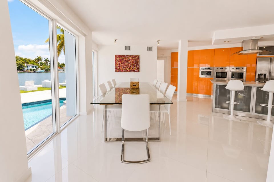 Bright waterfront dining space with pool views and sleek modern kitchen