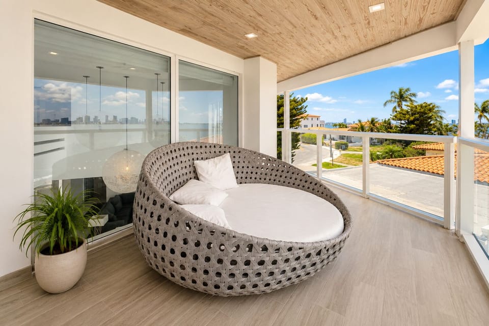 Relax on the stylish covered balcony with coastal views and a cozy daybed