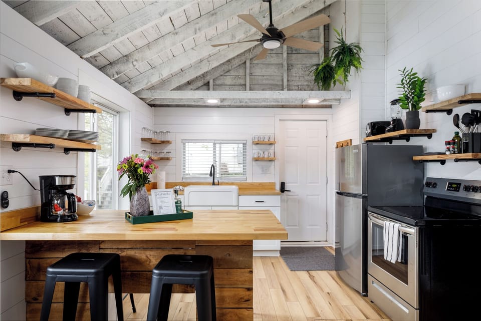 Bright kitchen w/ stainless appliances, wood counters & open shelving for a modern touch.