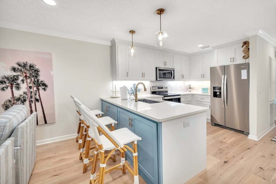 White kitchen with blue island, bar stools, and stainless appliances