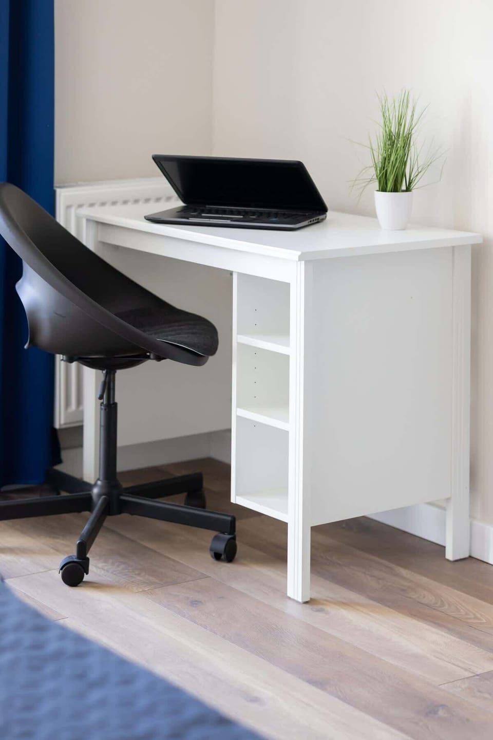 A small, functional workspace with a white desk and chair near a window, ideal for a minimalist home office setup.