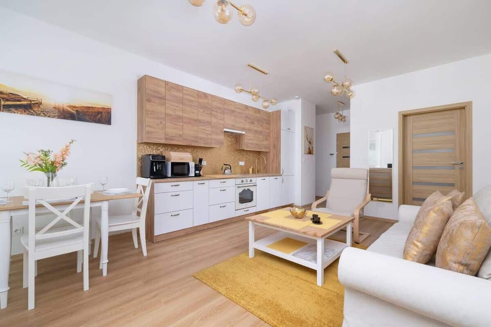 A modern living space with an L-shaped couch and a dining set in a natural wood palette.

