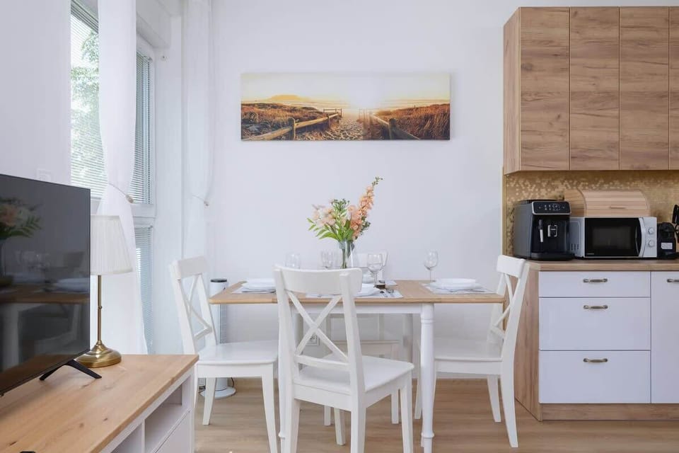 A dining area set next to a bright kitchen with white cabinets and wooden accents.

