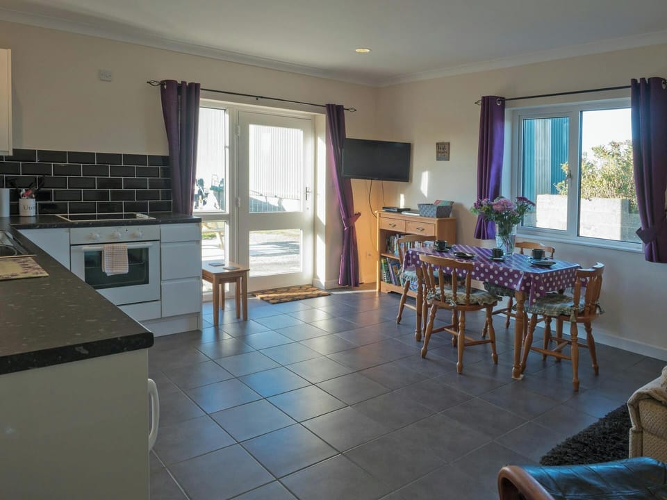 Dining table, chairs, sofa, bookcase, nest of tables, wall mounted TV and kitchen area