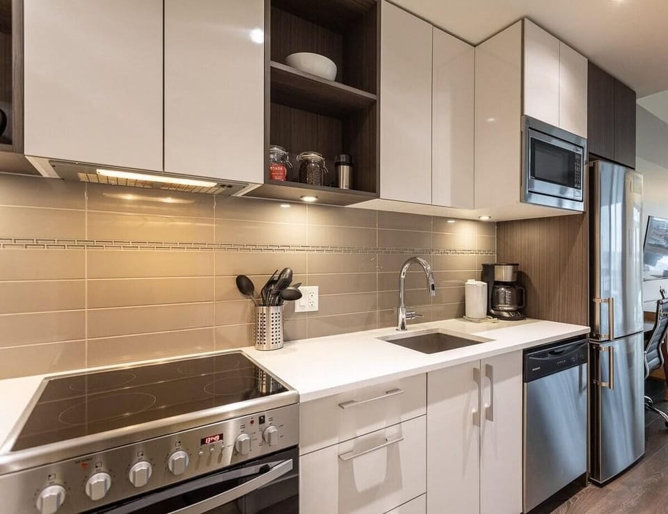 A fully equipped kitchen boasting modern cabinetry, crisp white countertops, a built-in range cooktop, and stainless steel appliances.