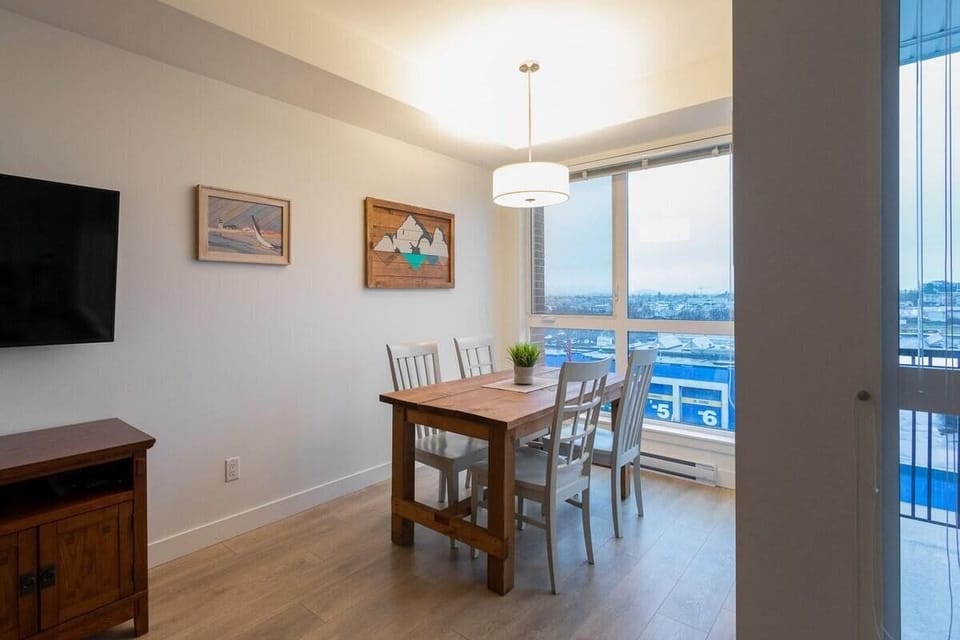 A charming dining table setup positioned next to large window panels, offering stunning neighborhood and water views during your meals.