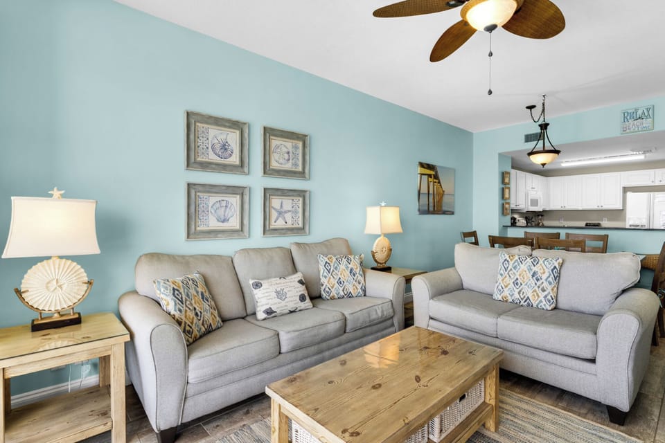Living Room - Relax in this coastal living space featuring a large flat-screen TV, beautiful decor, and a private balcony with breathtaking beach views.