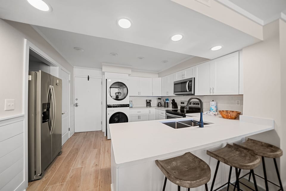 Your fully equipped modern kitchen awaits with gleaming countertops, stainless steel appliances, and a breakfast bar for morning coffee.