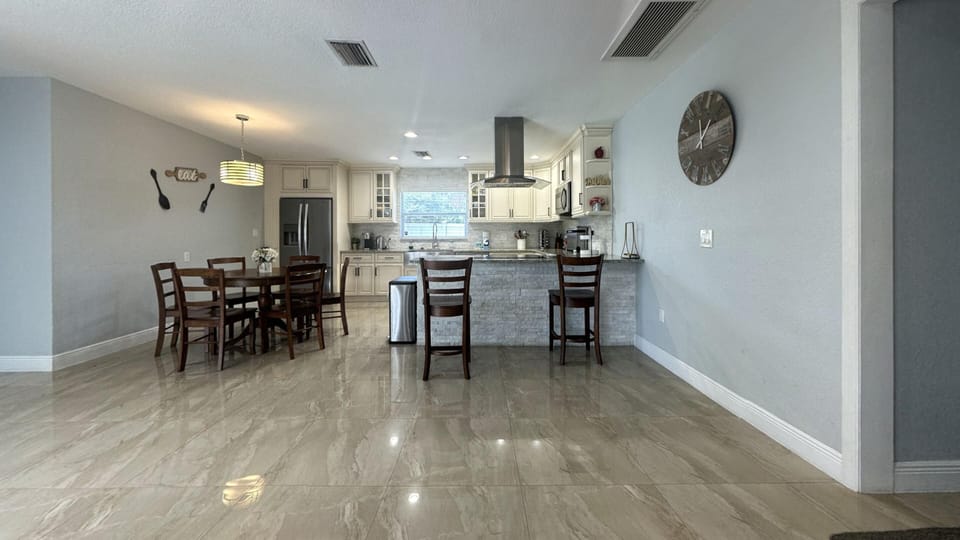 Open-concept dining and kitchen area with 6 seating dining table & 2 bar stools.