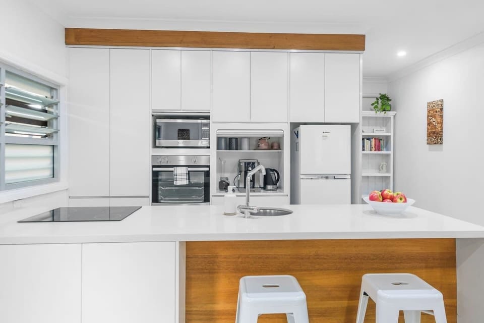 The kitchen designs are sleek and modern, with flush white cabinetry, an induction stove and tidy roller storage with a coffee machine 