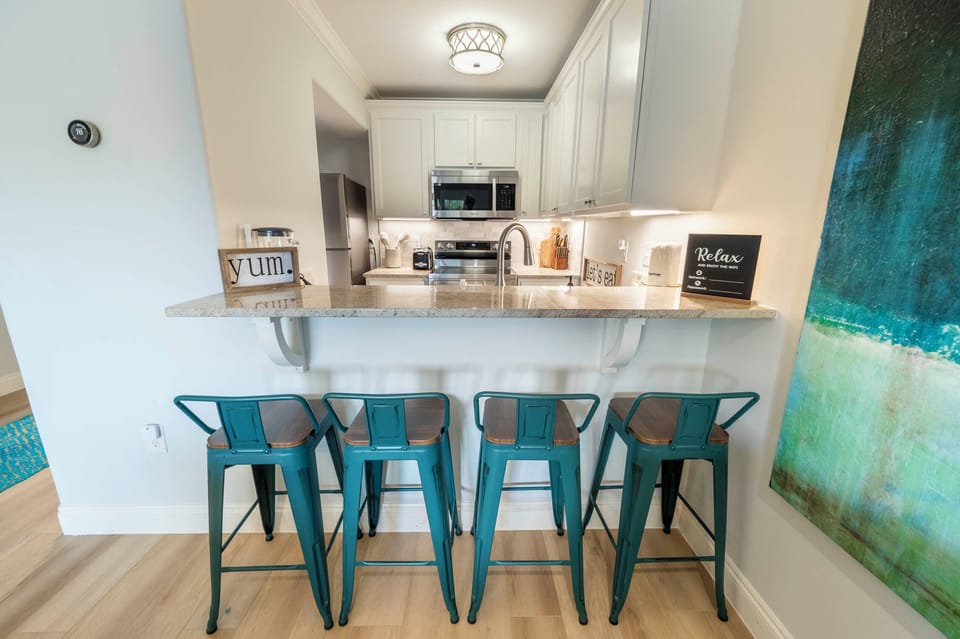 Stylish kitchen vibes: Teal stools, cozy ambiance, and modern granite design.