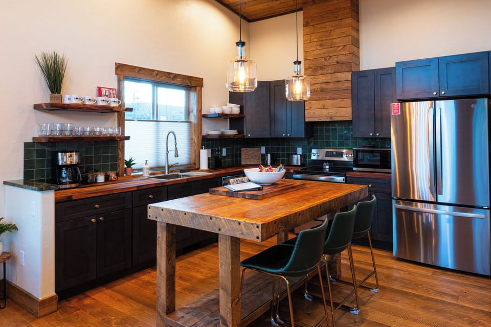 Full chef's kitchen with walnut butcher block countertops, dishwasher, range, hood, countertop microwave, and full-size refrigerator. Custom island with seating for 3. 