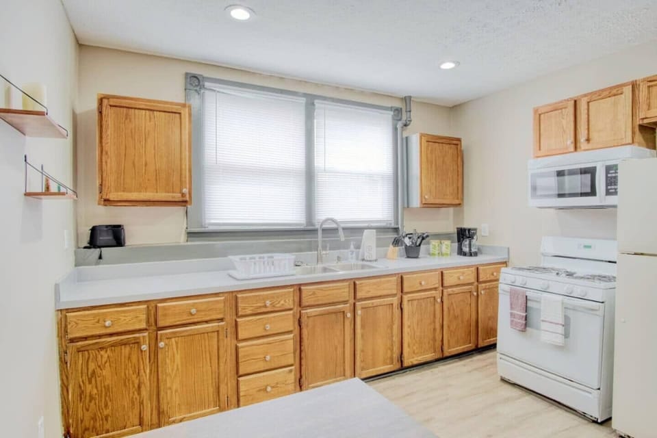 Transform your cooking experience in this beautifully designed kitchen featuring rustic wooden cabinets and state-of-the-art white appliances. 