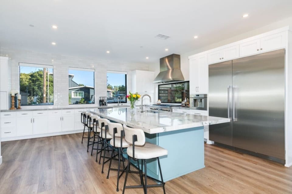 Feast in style with spacious seating, an island bar, white cabinetry, and a massive two-door refrigerator.