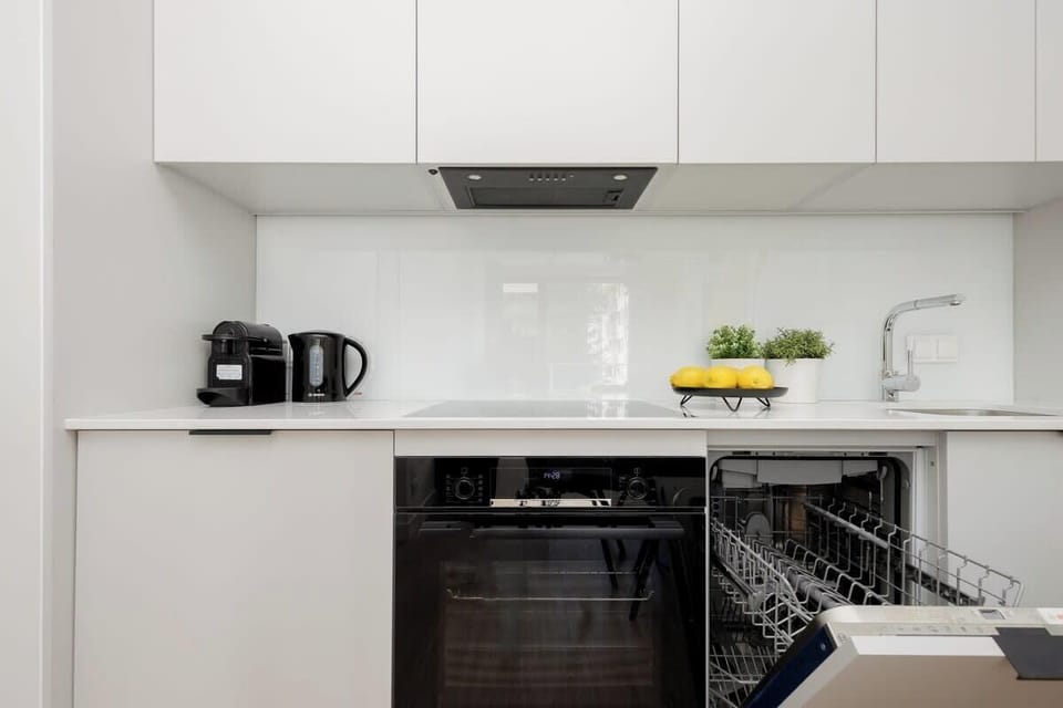 A compact kitchen area equipped with a coffee machine, kettle, and minimalist countertop accessories.
