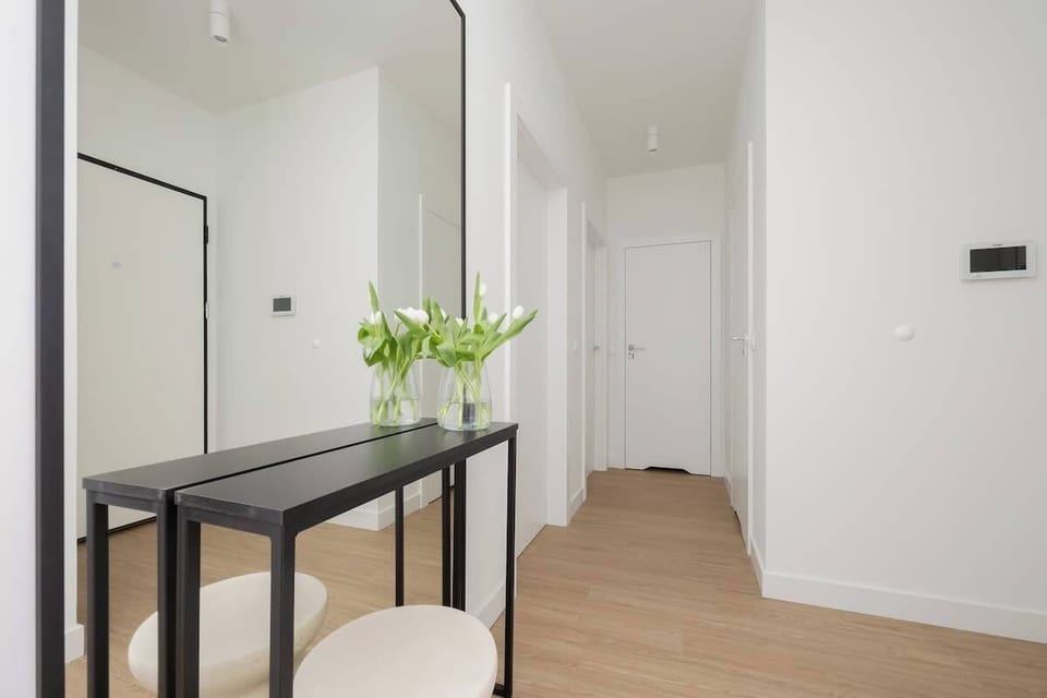 A hallway leading from the living area, decorated with a slim console table and a vase of fresh tulips.