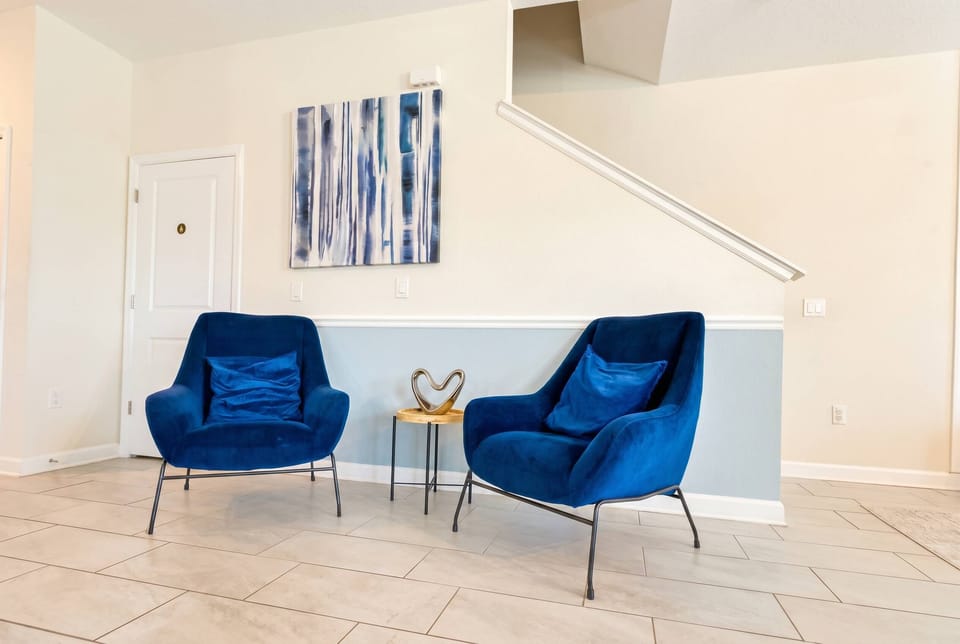 Cozy sitting area featuring two comfortable blue armchairs, a side table, and modern décor, creating an inviting spot to relax and enjoy quiet moments during your stay.