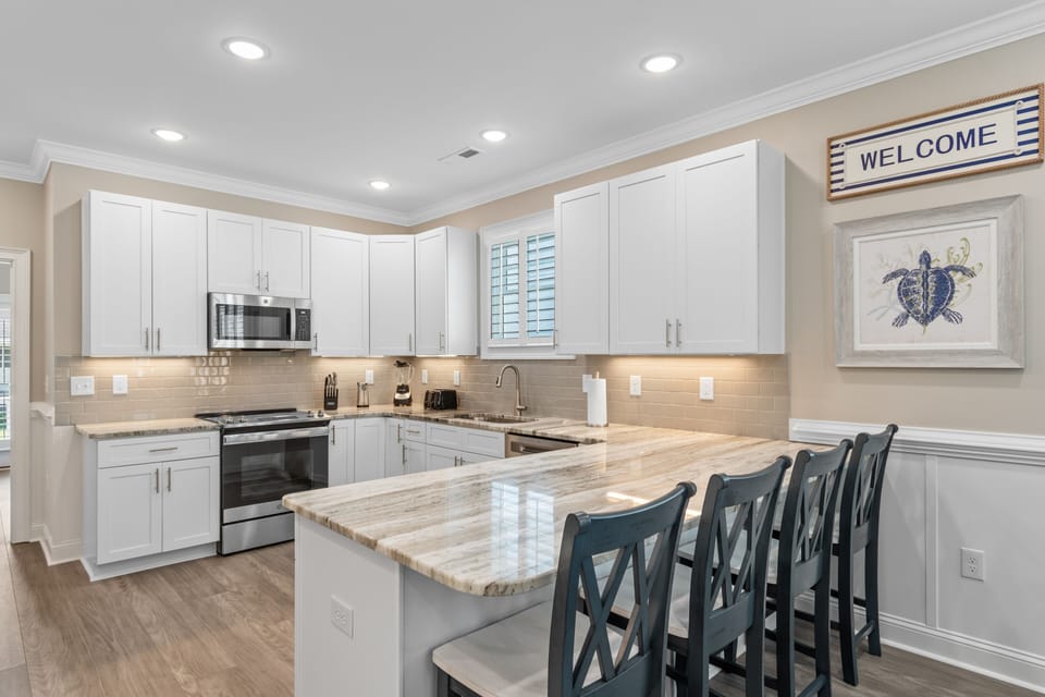 Prepare your favorite meals in this bright, fully-equipped kitchen featuring granite countertops, modern appliances, and a breakfast bar perfect for morning coffee.