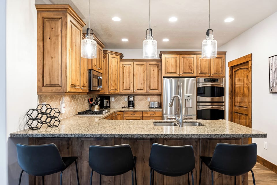 - Kitchen island with granite countertop and bar stools  
- Pendant lighting brightens the cooking space  
- Stainless steel appliances and ample storage space