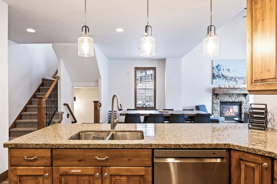 - Kitchen island view toward dining and fireplace  
- Open concept layout with modern pendant lighting  
- Easy flow from cooking space to social areas