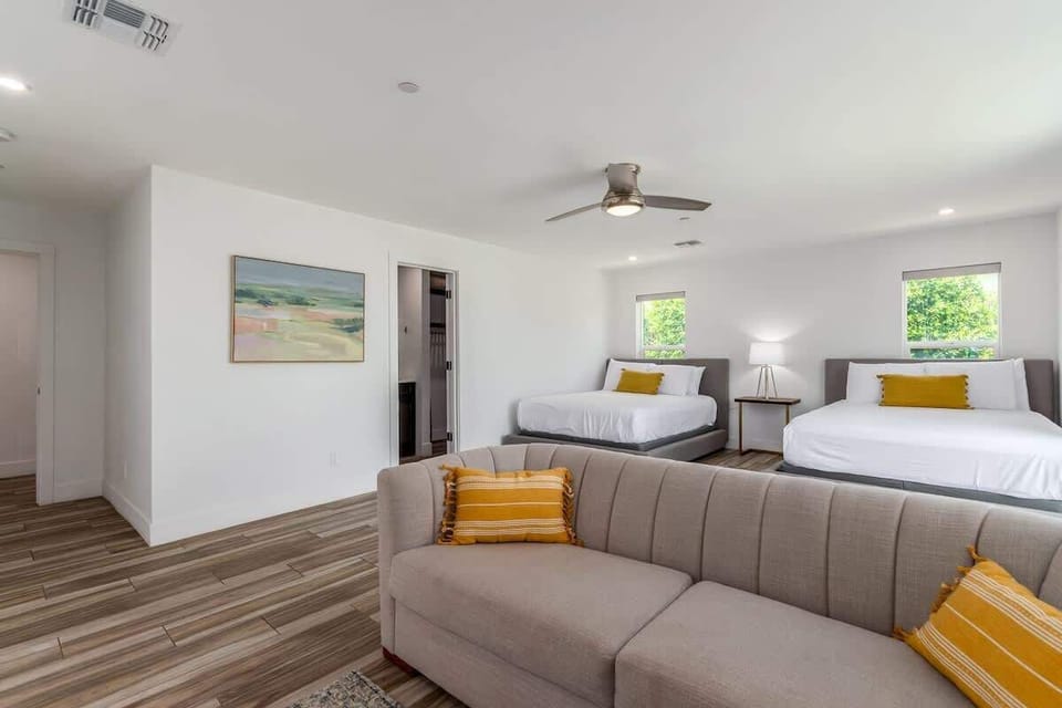 4th Bedroom featuring two queen beds, a couch, a smart TV, en-suite bathroom, walk-in closet, and access to the front of the house.