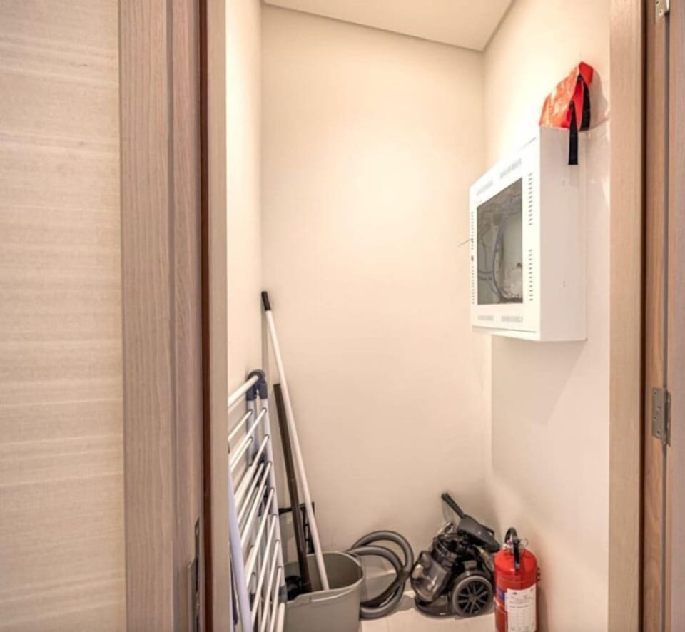 Stay prepared with the well-equipped utility room, featuring a fire extinguisher, cleaning essentials, and a convenient clothing rack for your needs.