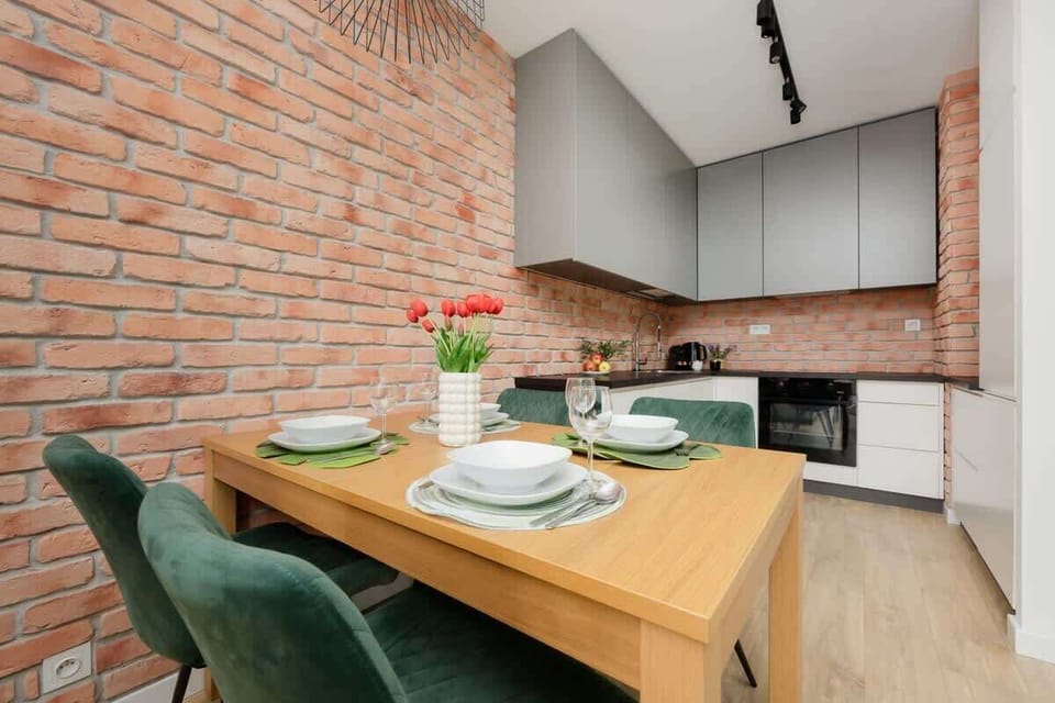 A kitchen and dining area combination, blending sleek cabinetry with raw brick for an industrial-modern look.