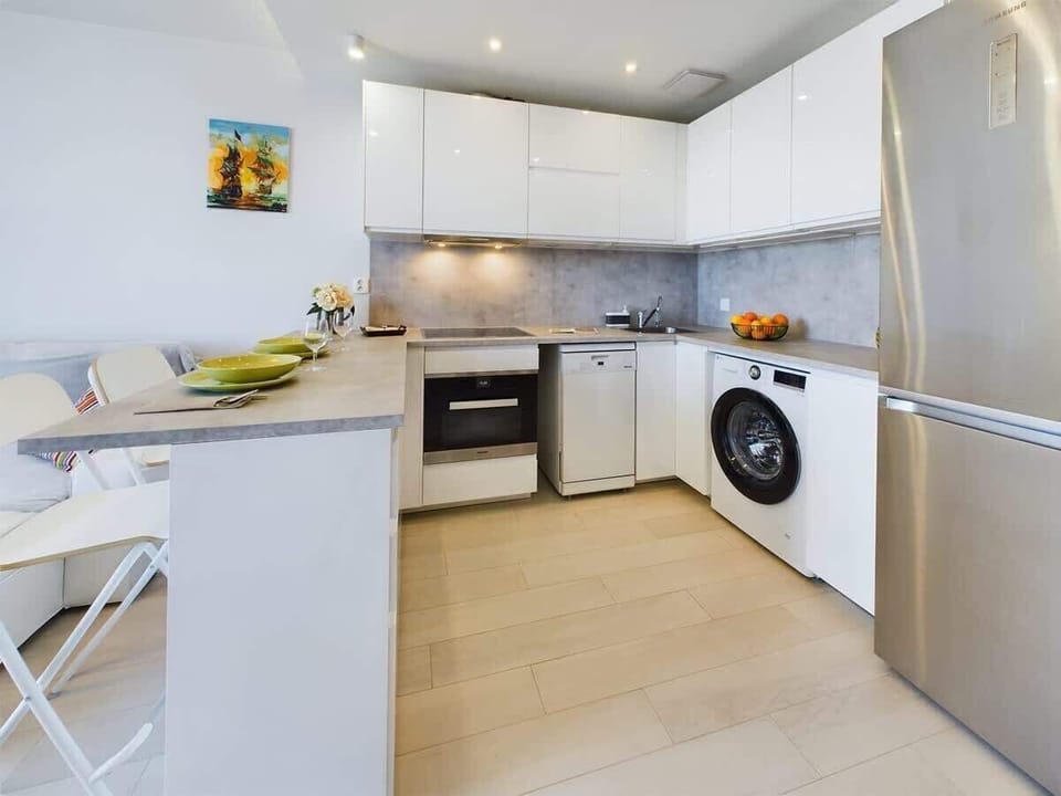 A wider kitchen angle showing the integrated oven, cooktop, and a cozy space with white cabinetry.