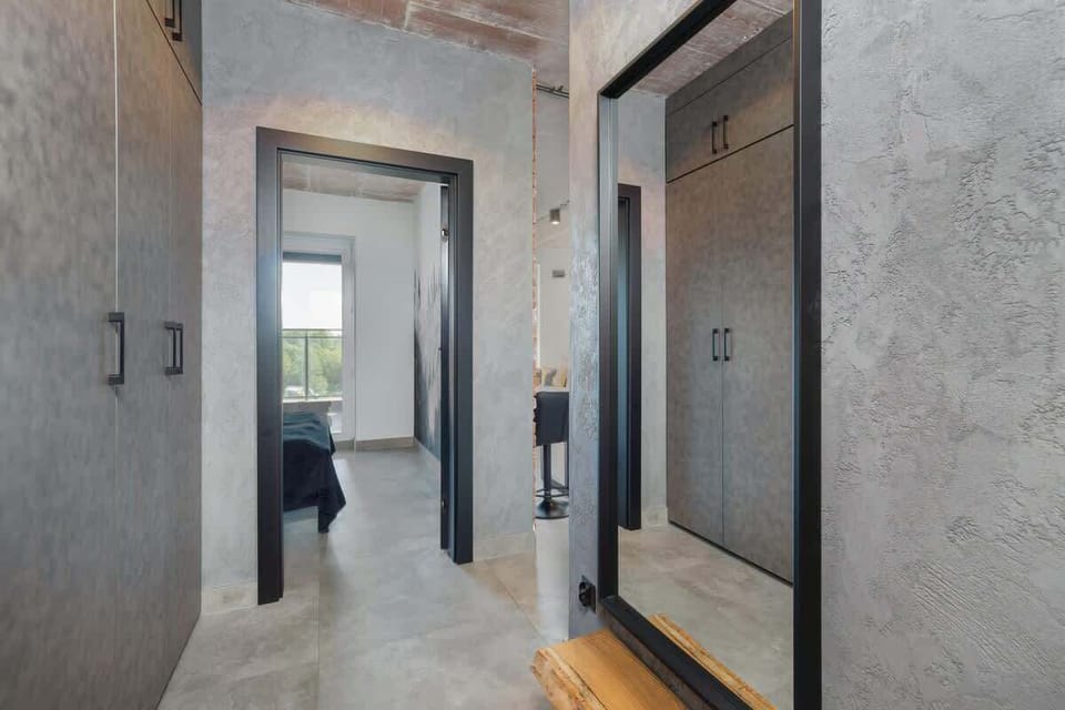 Minimalist entrance with clean concrete walls and smart lighting, setting the tone for a refined stay.

