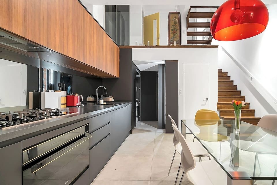 You’ll love cooking in the sleek kitchen designed with striking charcoal black flush cabinetry and benchtop complemented by a mirrored splashback and timber shelving. 
