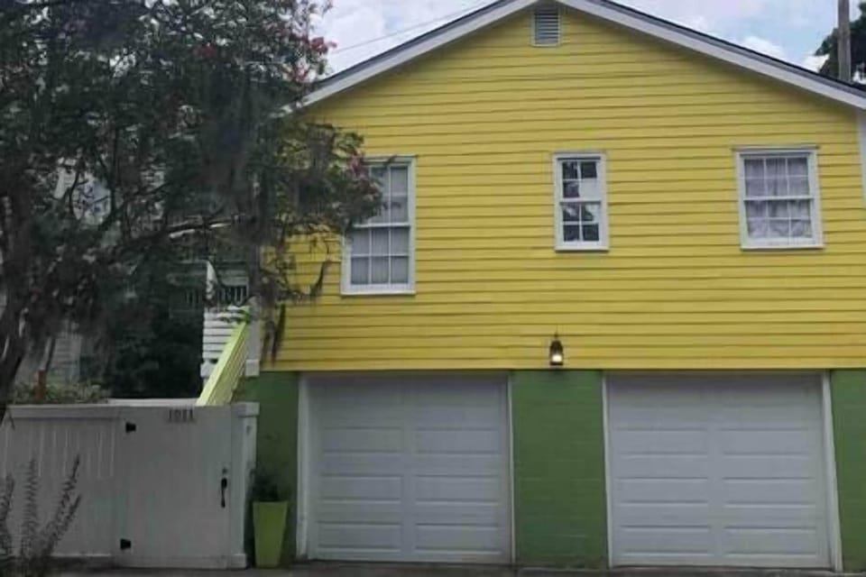 Street side of carriage house. Gate entrance left of garage doors. 