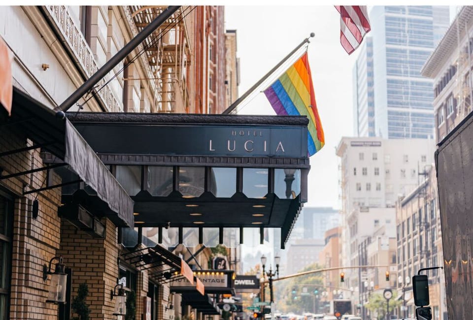 Hotel Lucia's charming exterior, welcoming guests with vibrant pride flags and a classic urban setting.