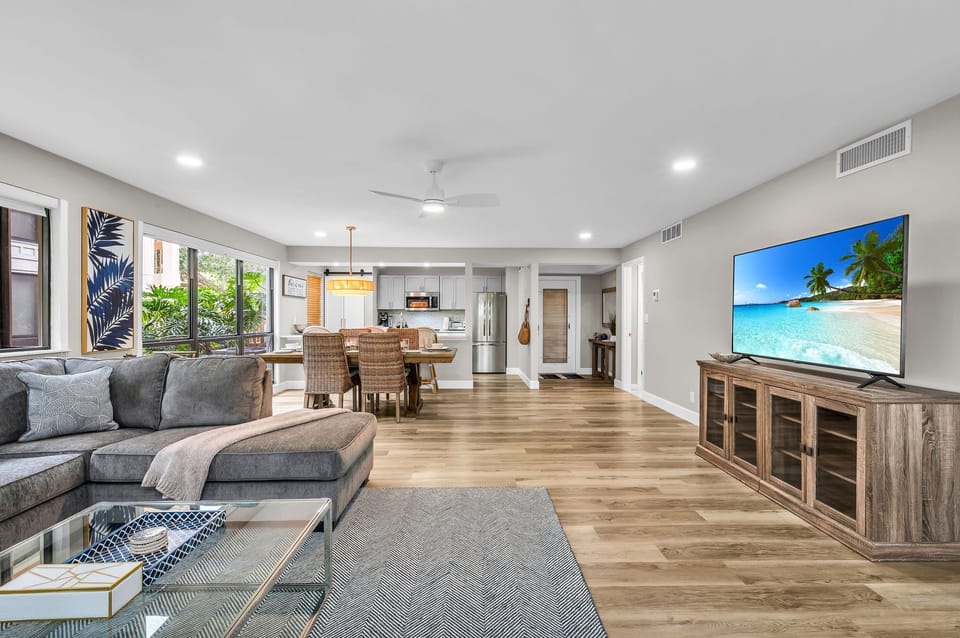 Modern living: Open concept living & dining area with large windows for ample natural light, and views for the golf course. The living room features a full-sized sleeper sofa, personal desk, and smart streaming TV with cable.
