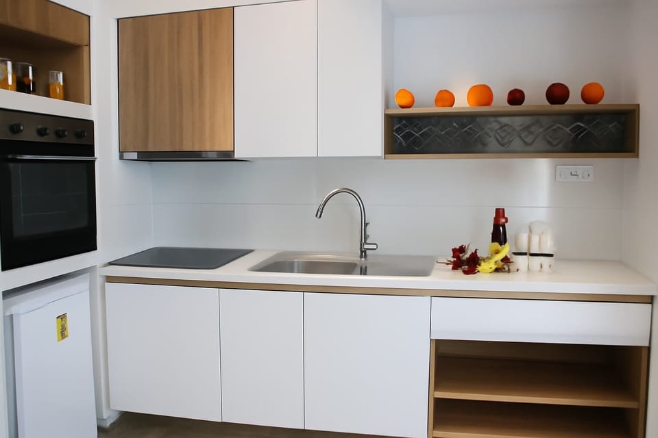 Kitchen area with open layout – Simple, white cabinetry and bright counter space.

