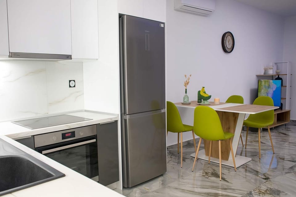 Fully Equipped Kitchen with Dining Nook
Sleek kitchen setup with built-in oven, tall fridge, and adjacent dining table for ease and comfort.