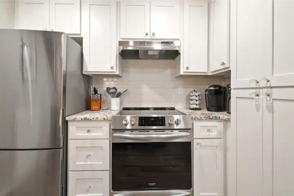 Stocked kitchen including cookware, coffee pods, spices, cooking oils.